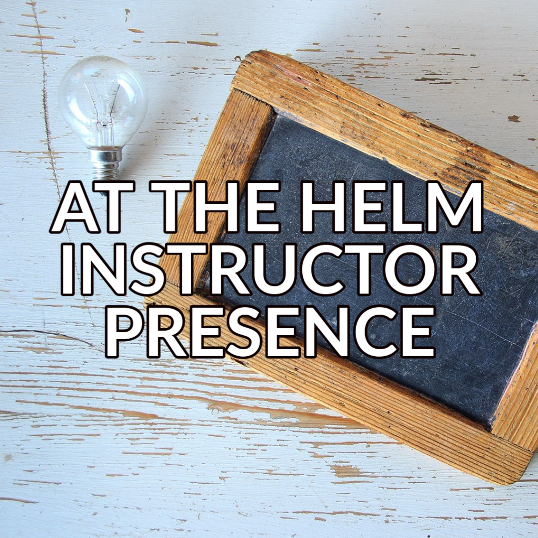 A button that reads "At the helm - instructor presence" in white text with a black outline over a background image of a chalkboard and a lightbulb on a light colored table